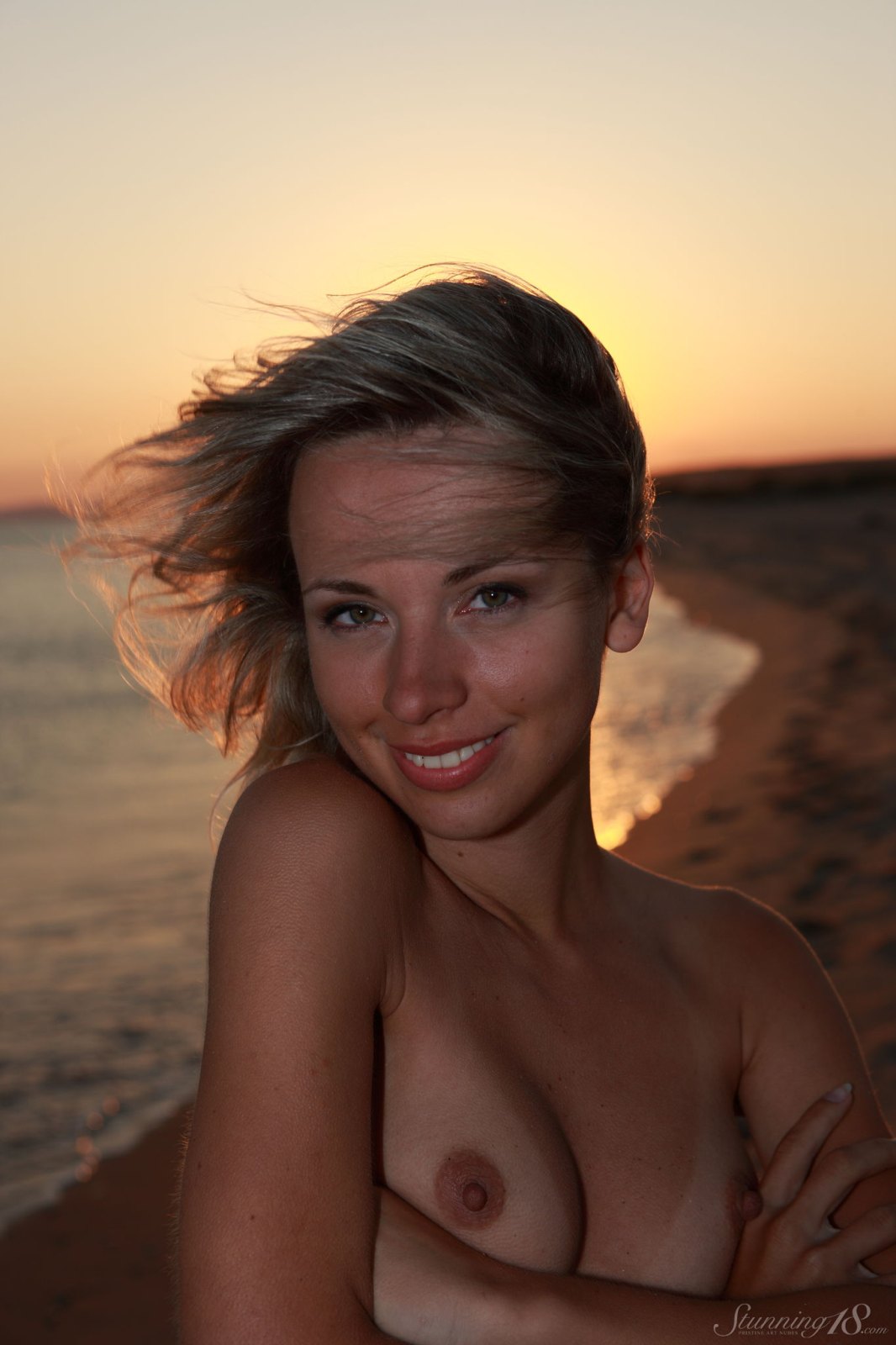 Cute petite blondie playfully poses naked on the beach in the sunset  in Stunning 18 set Sunset