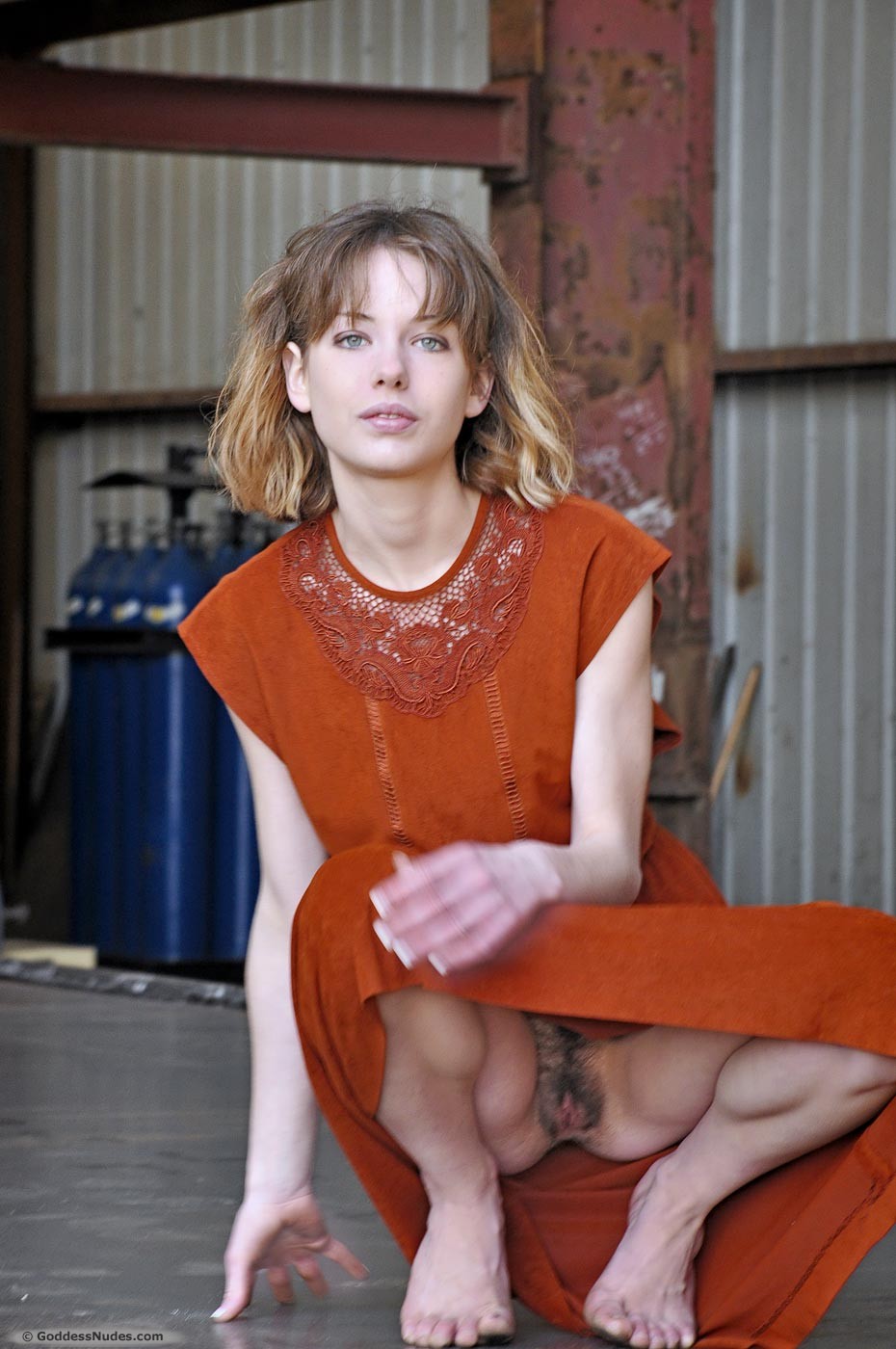 Model wears beautiful burnt orange shift dress and exposes bare bottom underneath