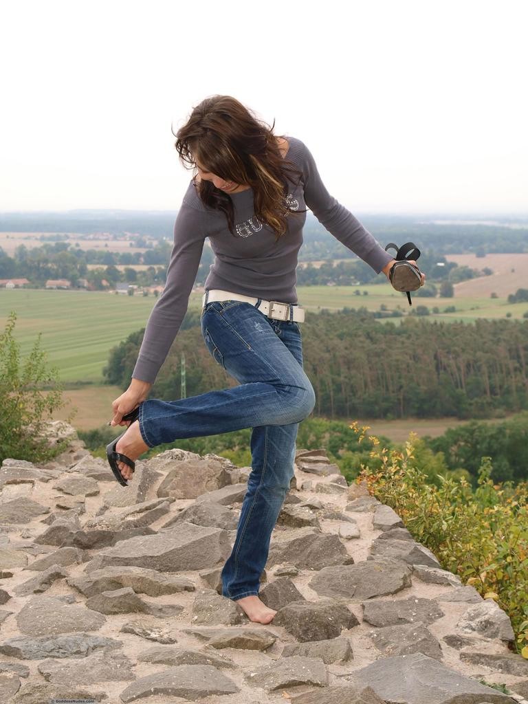 Sylvia slips out of her blue jeans and heels to stand proudly nude atop hill